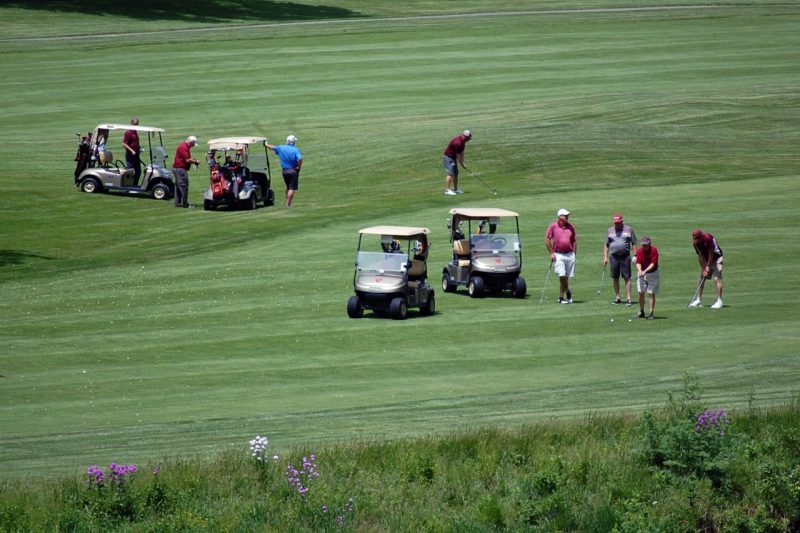 Golfers and carts on the course.